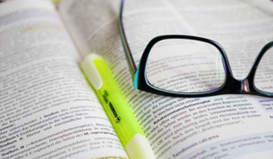 An open book, highlighter and glasses