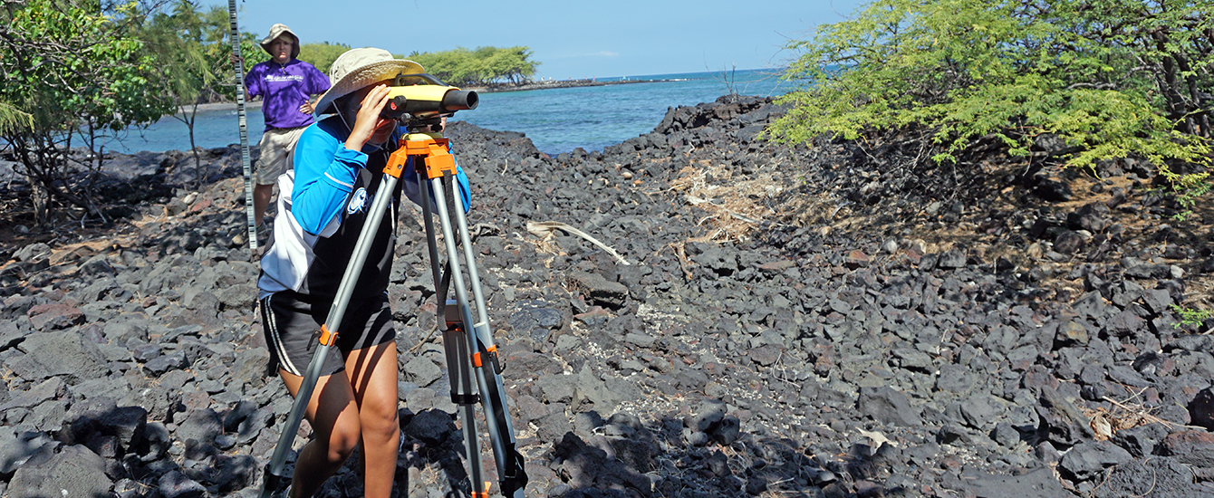一名学生在夏威夷的海滩上用望远镜看东西