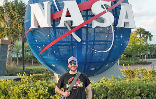 J.P. 伯克，十大平台网赌校友和NASA雇员，站在NASA标志前