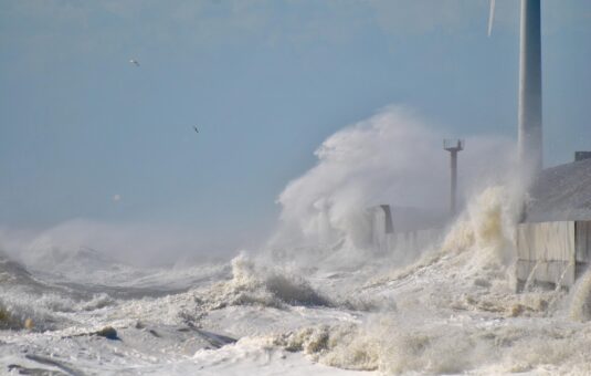 汹涌的海浪拍打着风力涡轮机下面的混凝土墙