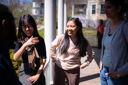 研究生 学生 gather for a casual conversation on the porch of the 部门 Sustainability 和 Social Justice building
