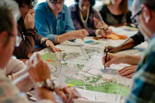 Policy makers seated at a conference table discussing plans for community green spaces.