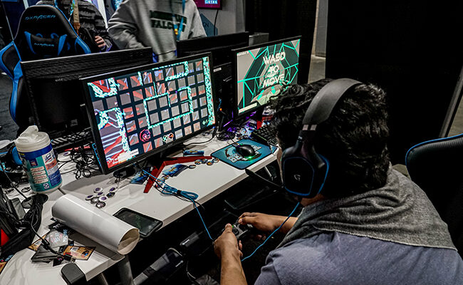 在PAX East 2020上，戴着耳机的玩家正在玩游戏
