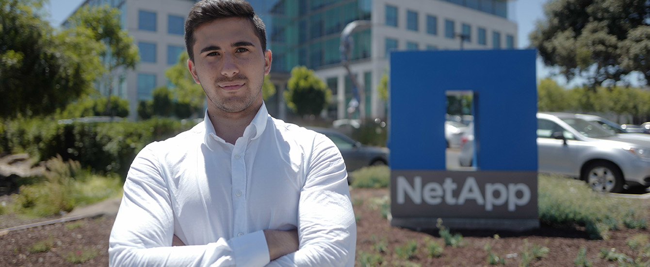 Student standing in front of NetApp sign