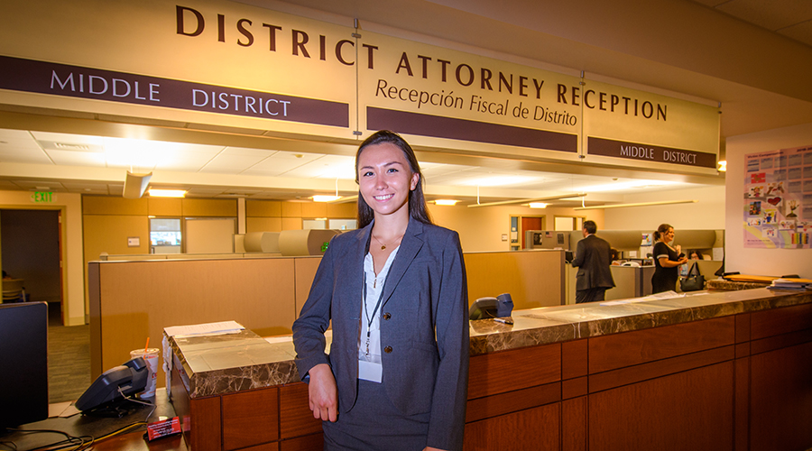Female student sitting in front of District Attorney sign