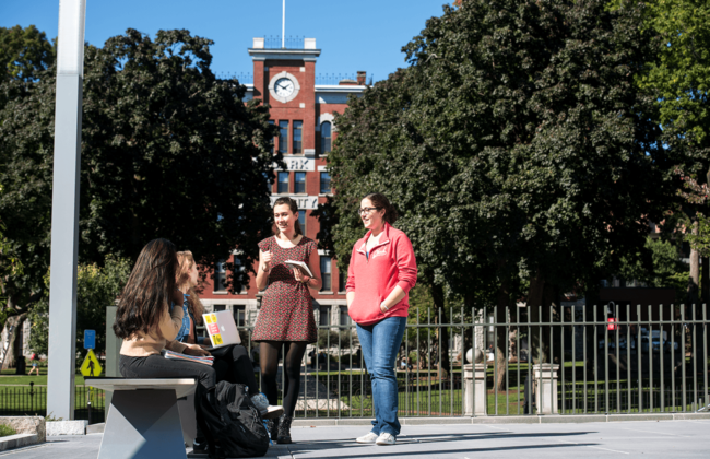 Image of students and standing having a conversation in front of Jonas Clark Hall.