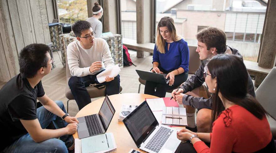 business economic students around table with laptops