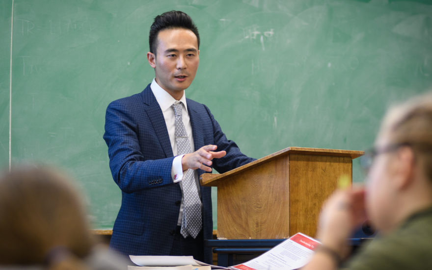 asian male standing in front of class at podium