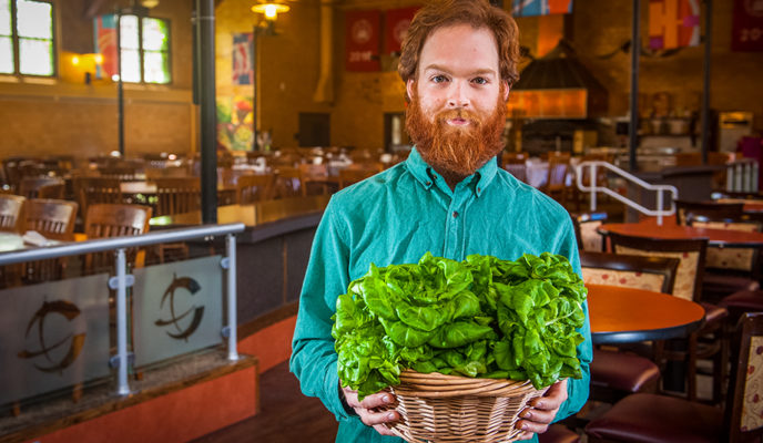 男性抱着一篮子绿叶蔬菜