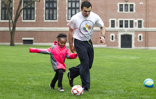Student playing soccer with chil