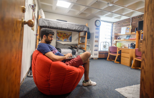 male sitting in dorm room