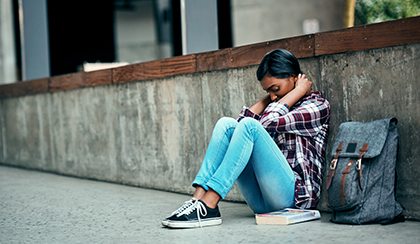 sad student sitting alone on sidewalk