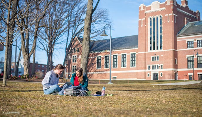 Students seated outdoors on the main campus green, Clark University