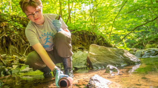 student collects water sample