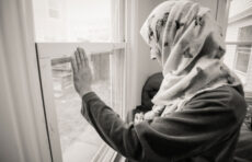 一个难民抱着她的孩子望着窗外