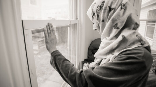 一个难民抱着她的孩子望着窗外
