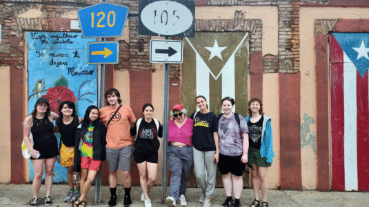 Group of Clark students posing in front of mural on wall in Puerto Rico