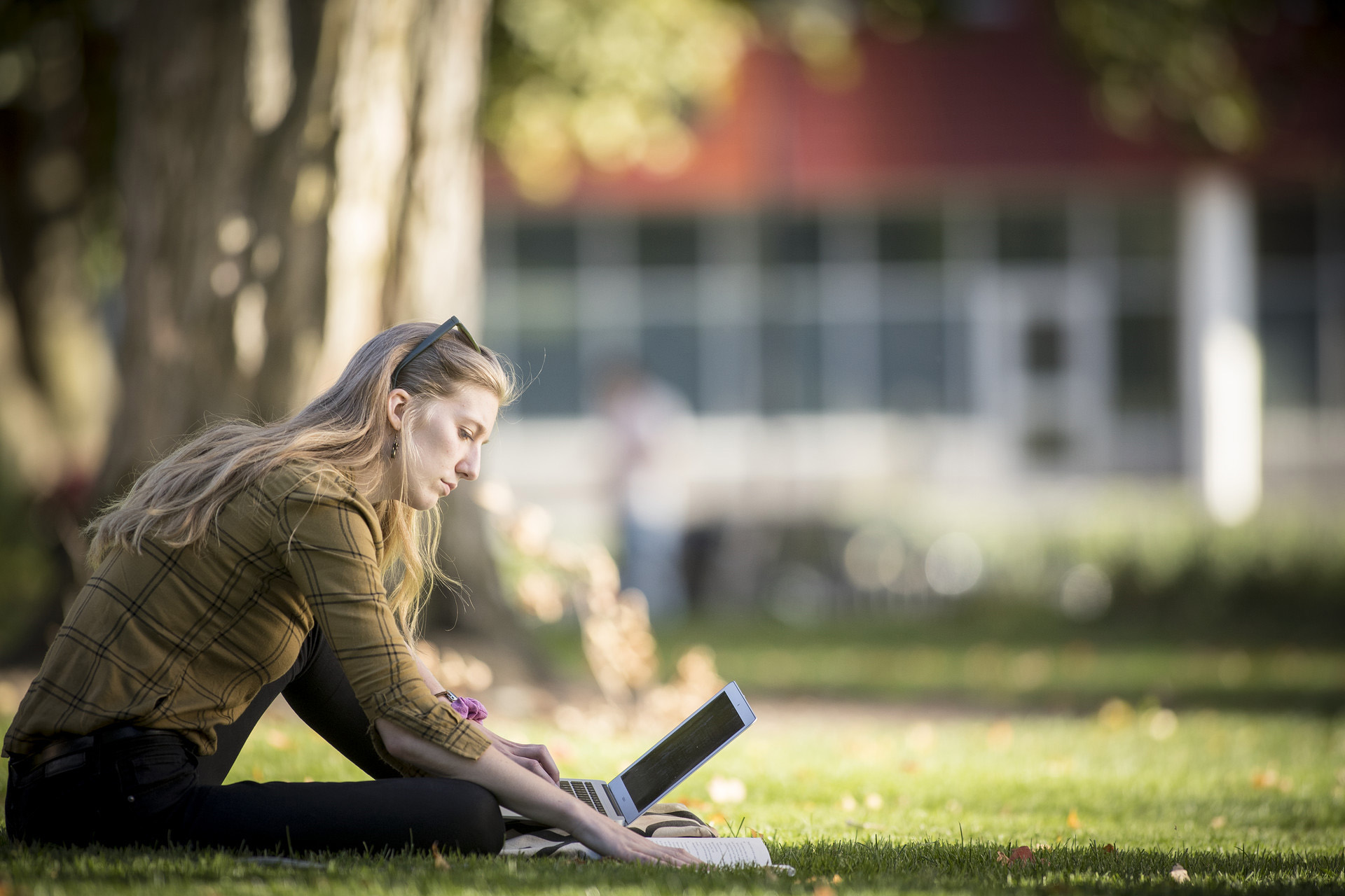 female student sitting on grass with lapto