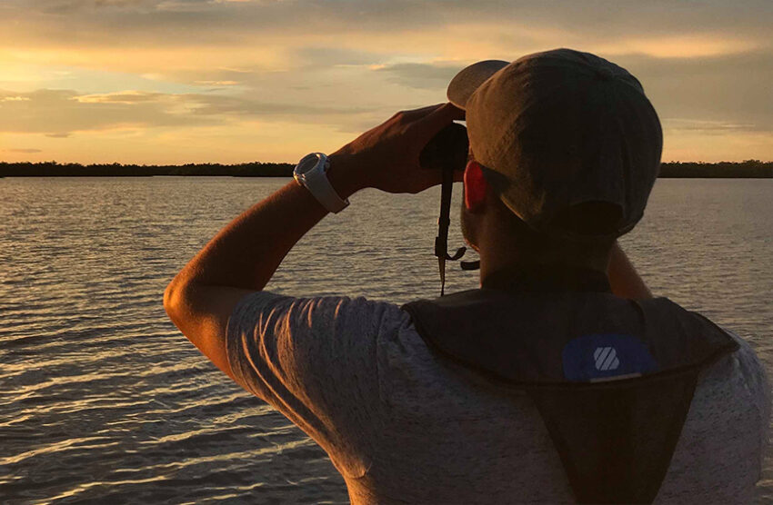 Young person looking across horizon with binoculars