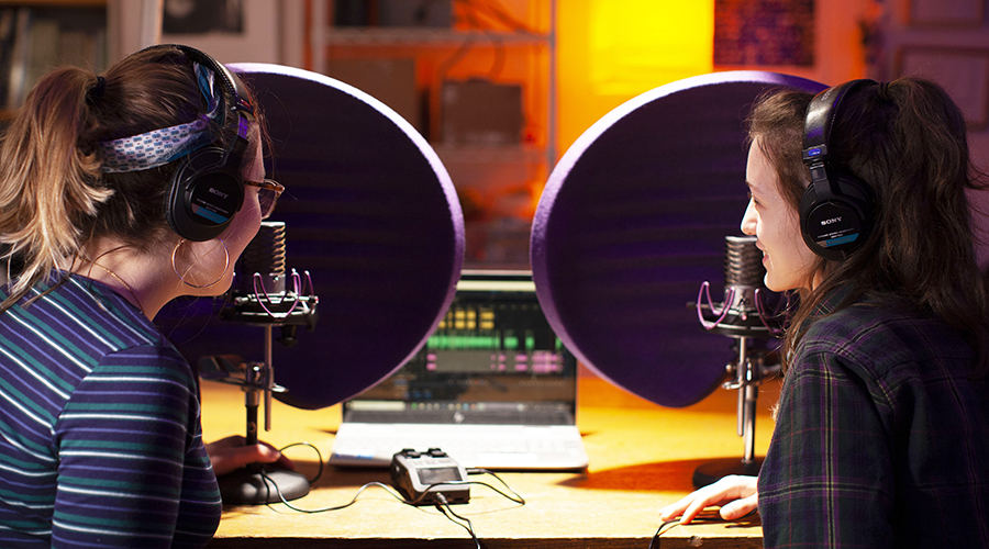 two media students speaking into microphones in studio