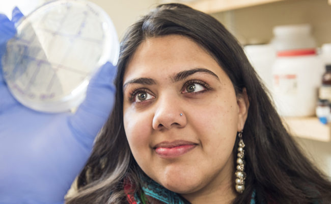 Christie Joyce holding up petri dish in lab