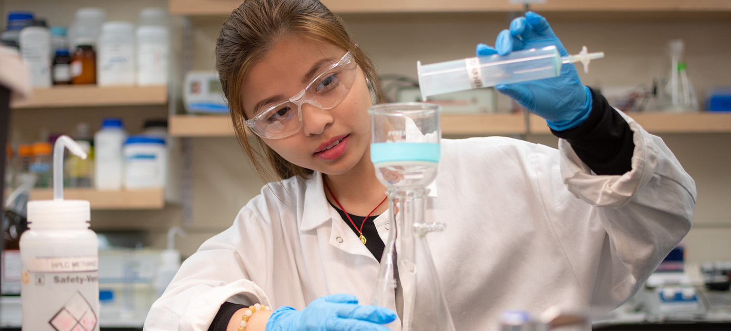 girl in research lab pouring chemicals in a tube