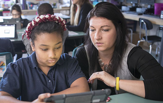 Education student working with elementary student in classroom