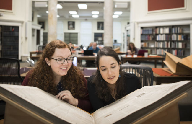 two girls looking at large book
