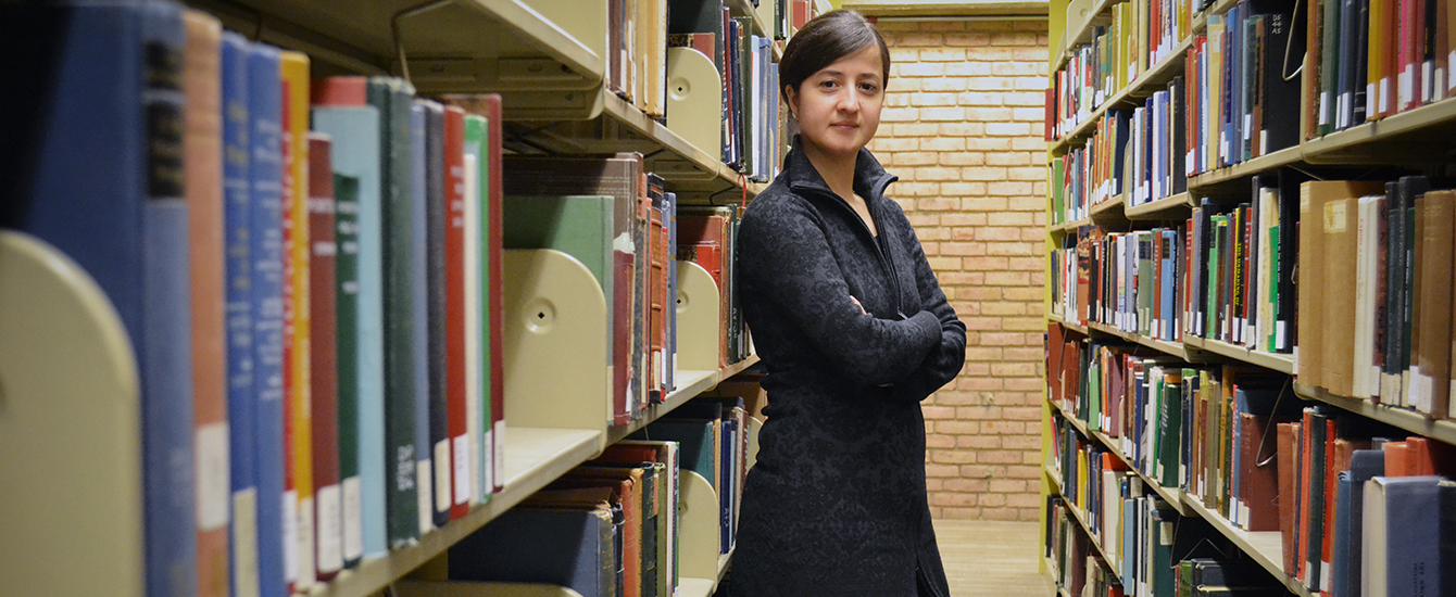 Student standing in book stacks in library