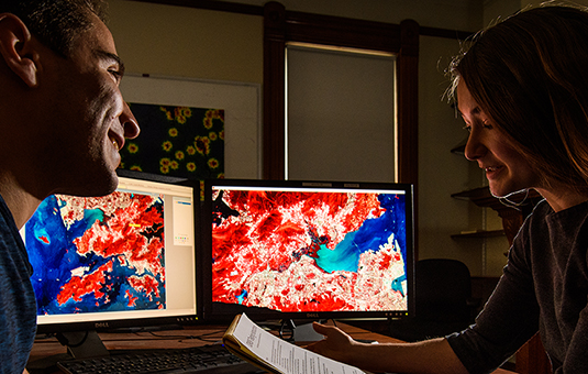 Two students working with GIS data on computer