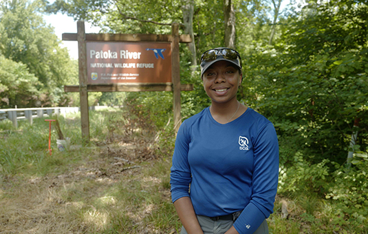 female student sitting in front of sign for Patoka River