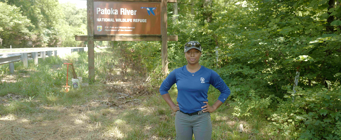 Environmental Science Student Olivia Barksdale standing in front of Pakota River wildlife refuge sign