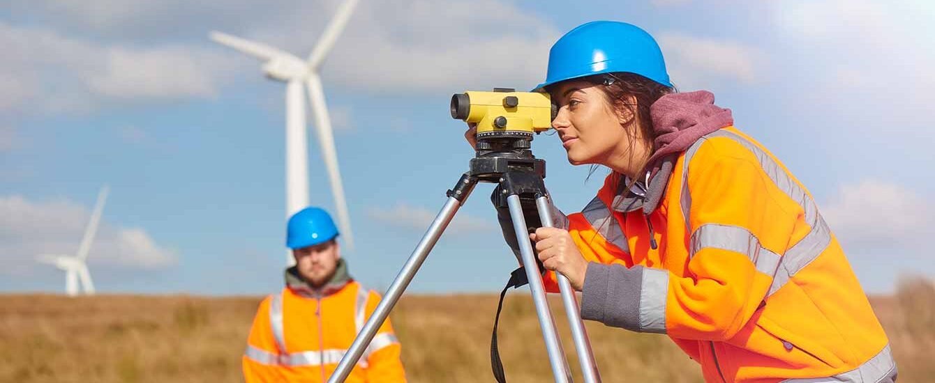 An environmental engineer conducts a land survey at a wind farm site
