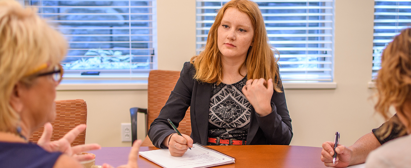 Student intern sitting at table meeting with employers
