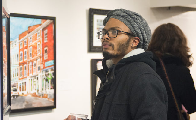 male student looking over art at show