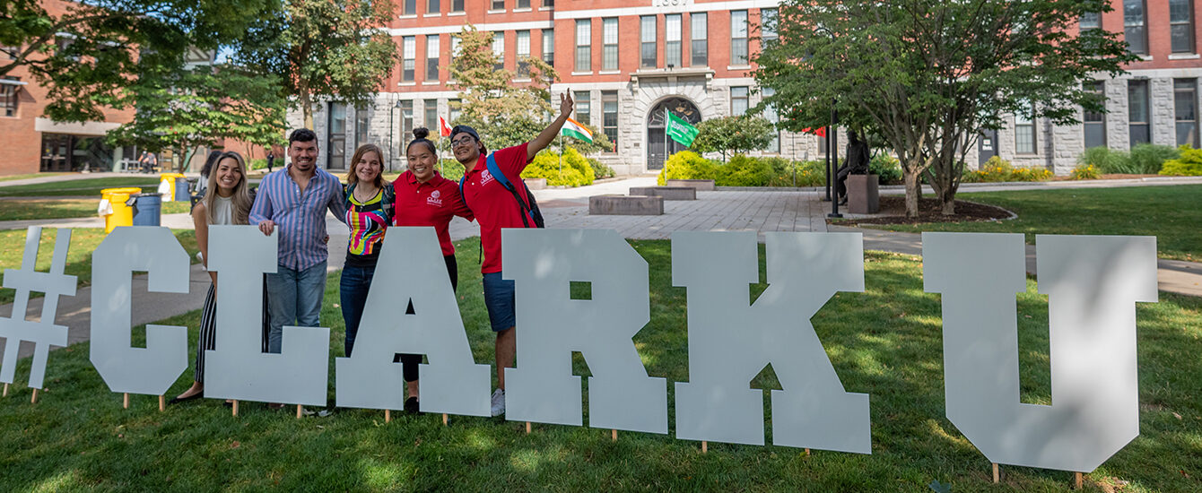 graduate students celebrating graduate student appreciation week and standing in front of #clarku sign