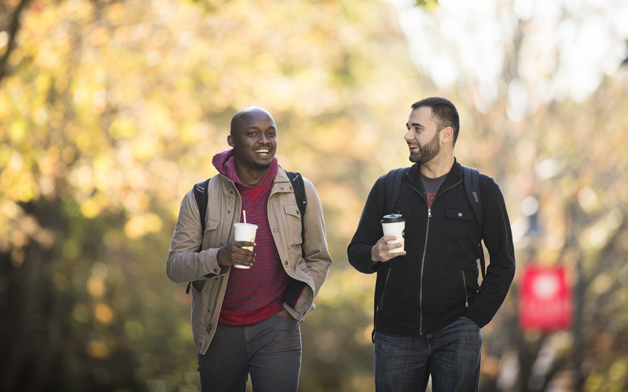 Graduate students walking down path with coffees