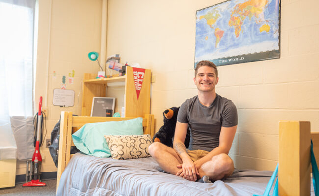 Bullock Residence Hall - young man sitting on bed