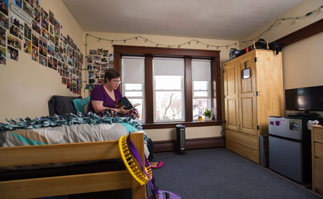 graduate housing: 926 Main St. Apartment Bedroom with woman sitting on be