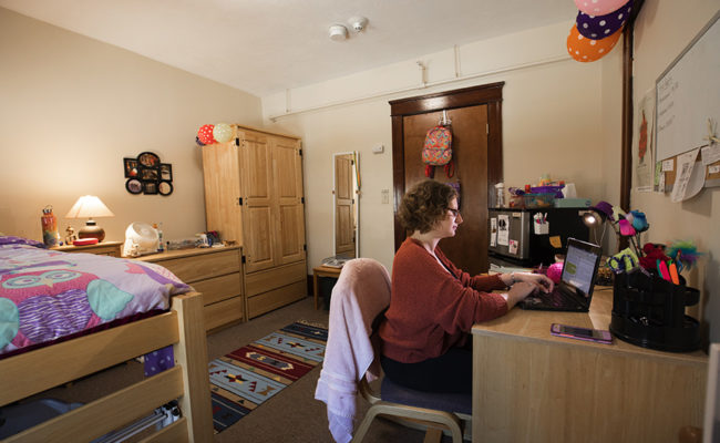 graduate housing: 926 Main St. Apartment Bedroom with female sitting at desk