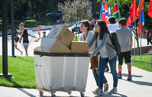 Student and mother pushing cart full of boxes