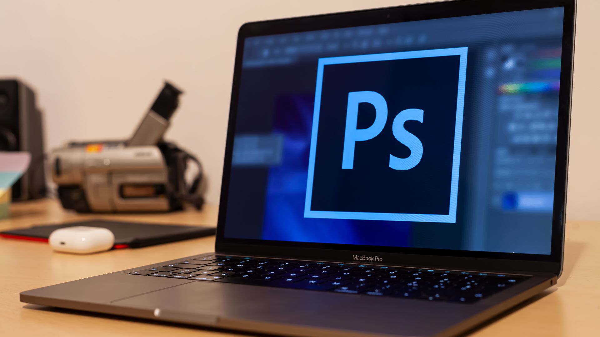 Laptop sitting on a desk. The screen shows the Photoshop logo
