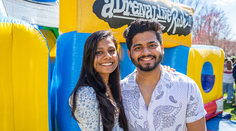 two students standing in front of bounce house on spree day