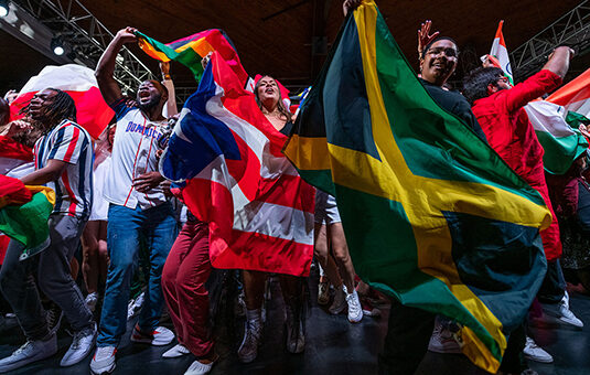 students participating in event holding international flags on stag