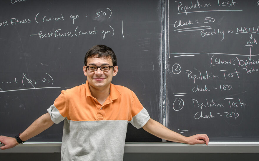 Student at chalkboard with formulas written on it