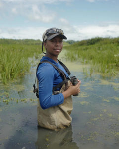 Student standing in a swamp