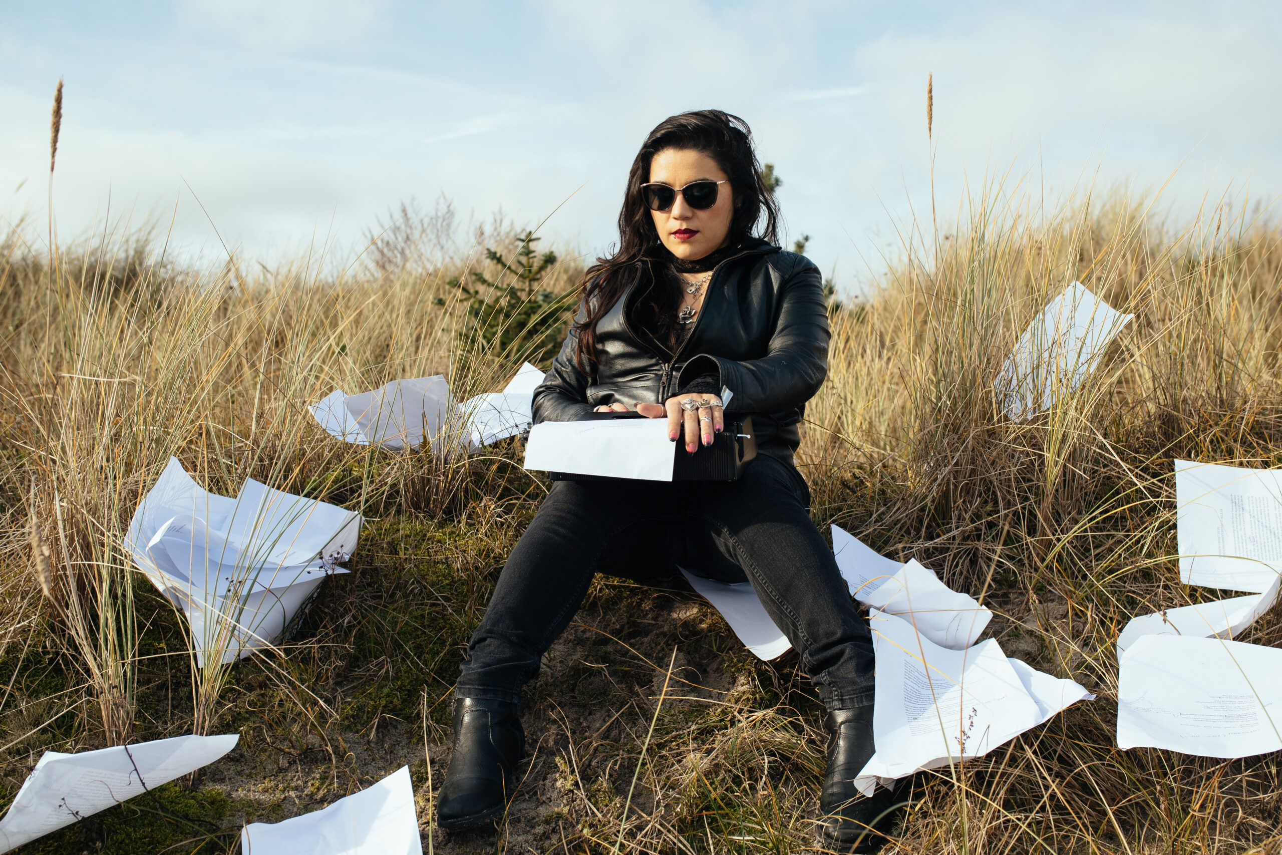 Elizabeth Torres sitting in tall grass with papers strown about her.