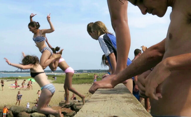 People jumping onto sand at beach