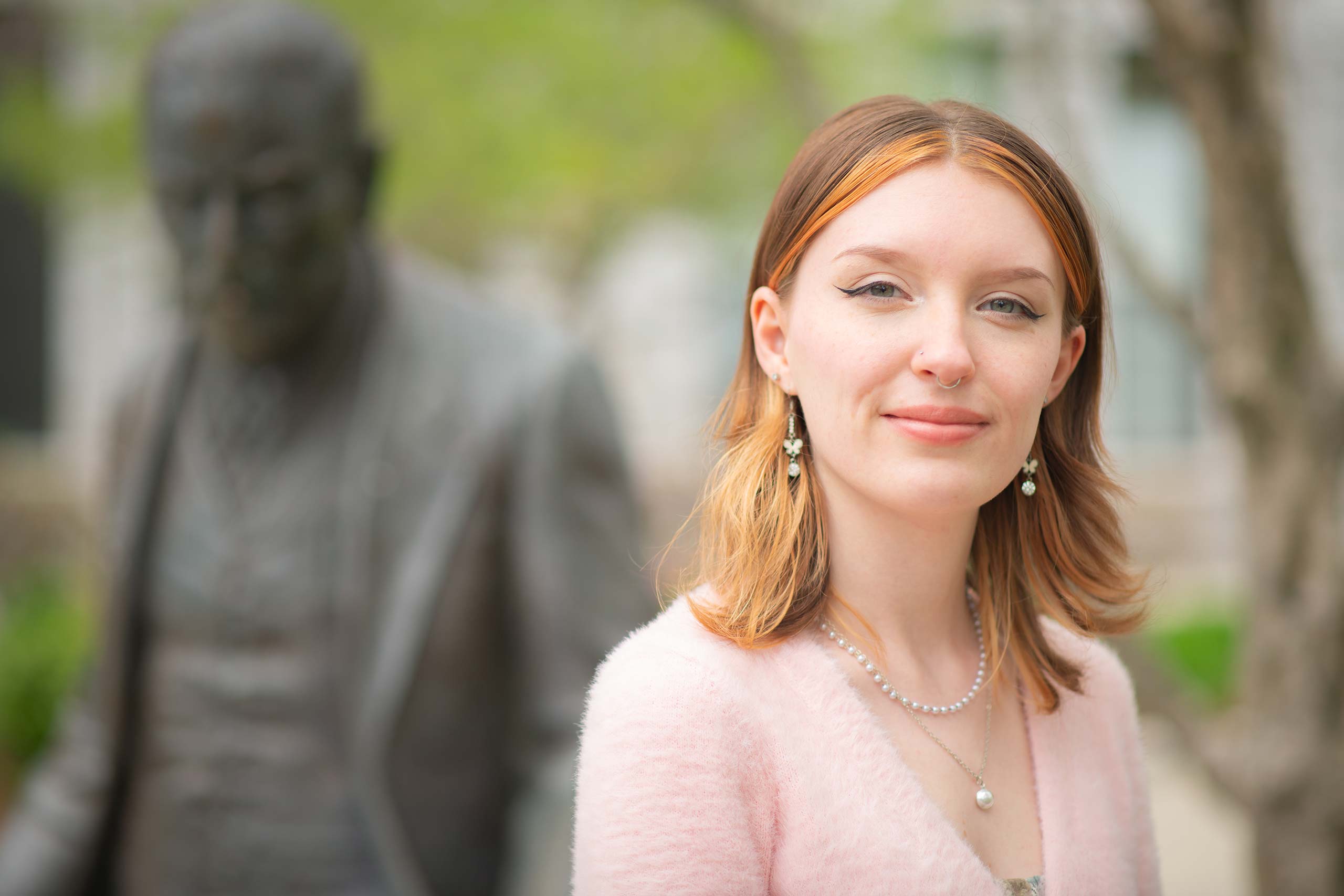 Katie Healey ’24, psychology major seated in front of the statue of Sigmund Freud, Clark University
