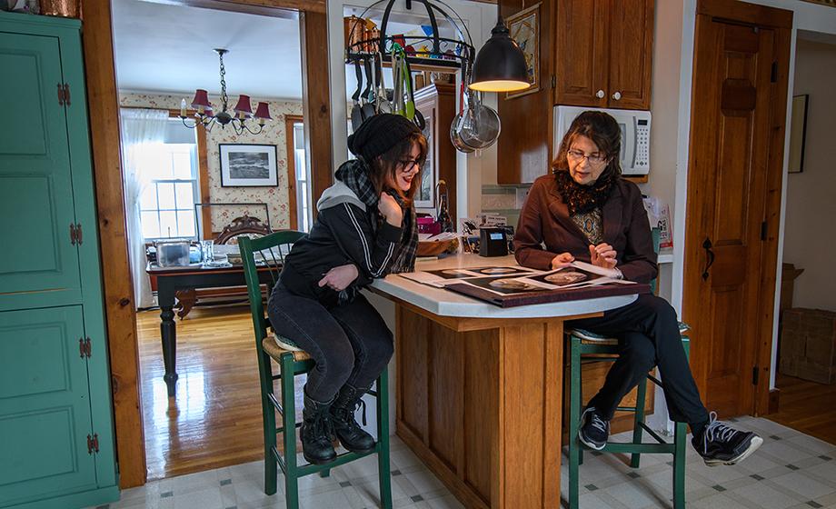 student sitting in kitchen with artist reviewing art